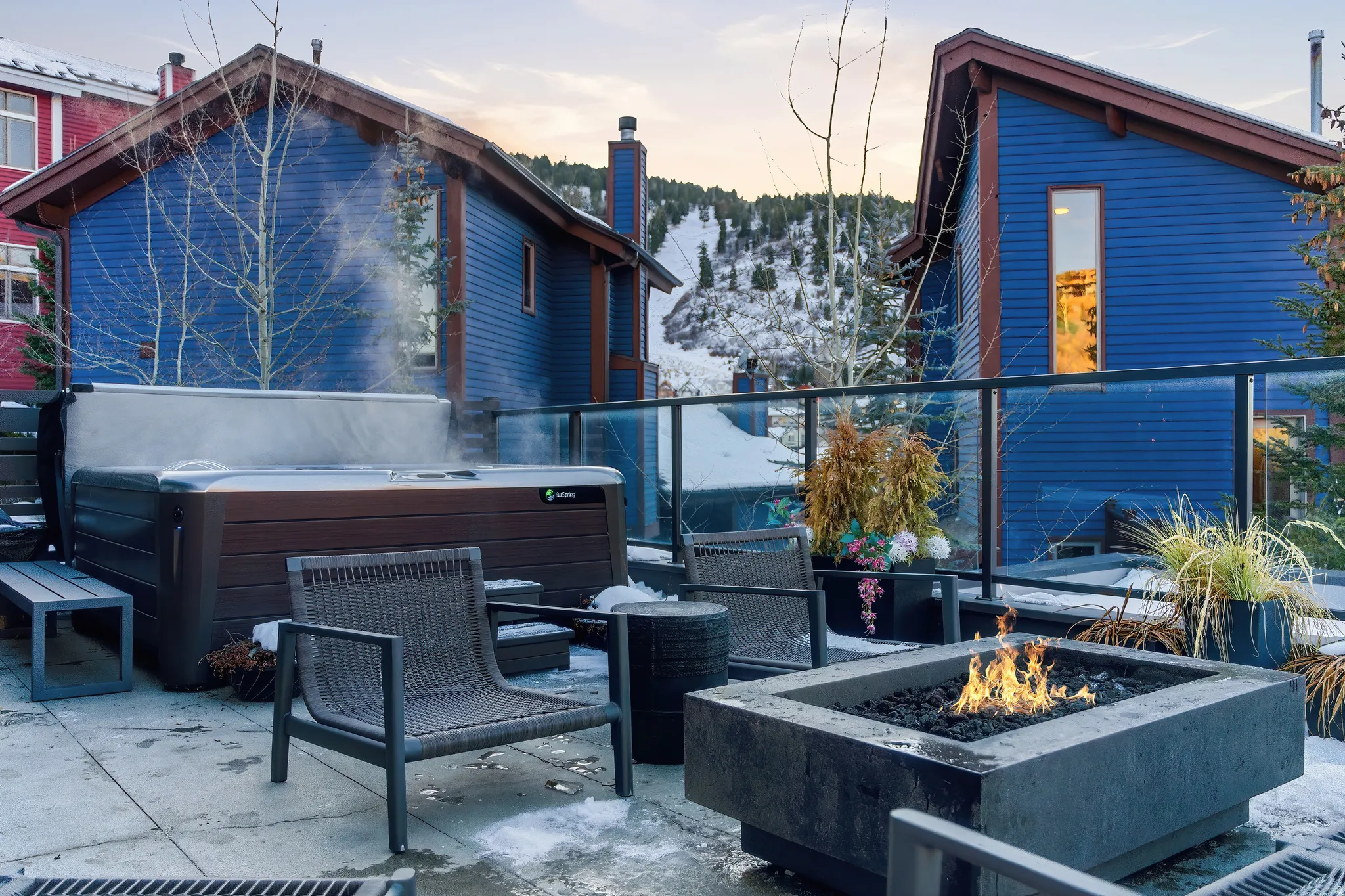 Spacious outdoor patio featuring a hot tub, a built-in fire pit, and a glass-paneled railing