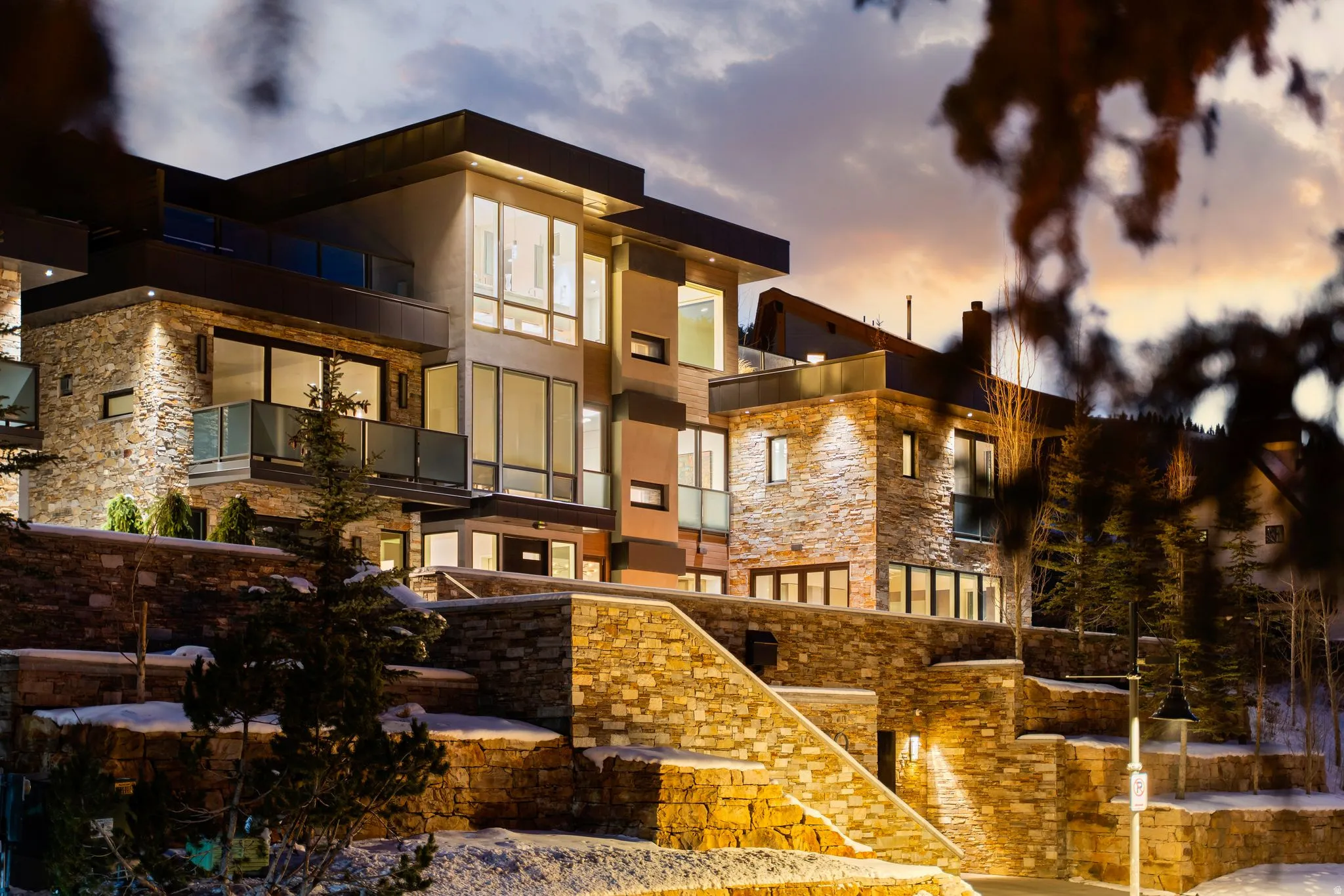 Modern multi-level exterior featuring stone cladding and expansive windows