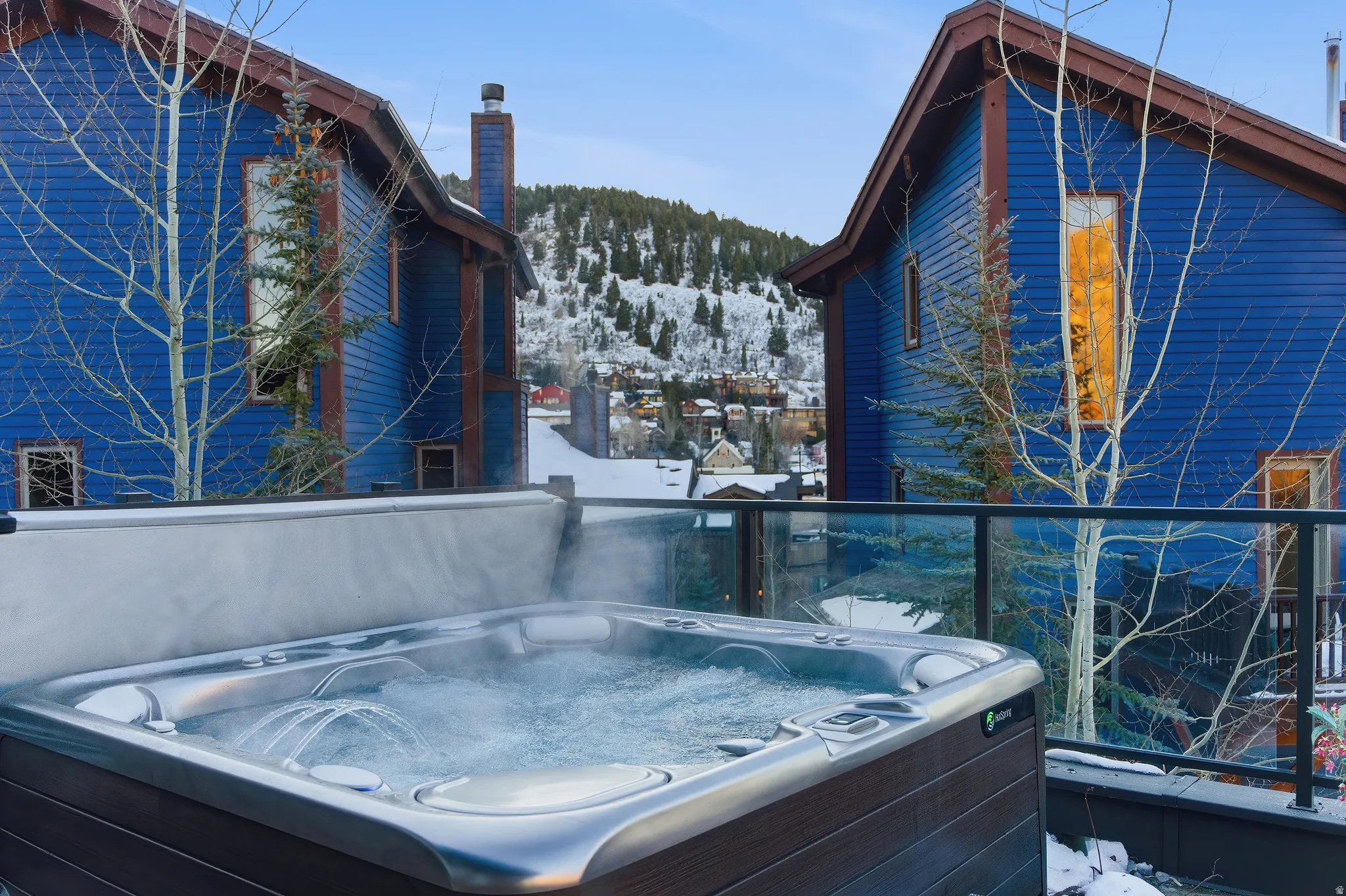 Deck-mounted hot tub with bubbling water, set against a backdrop of a snow-covered hillside