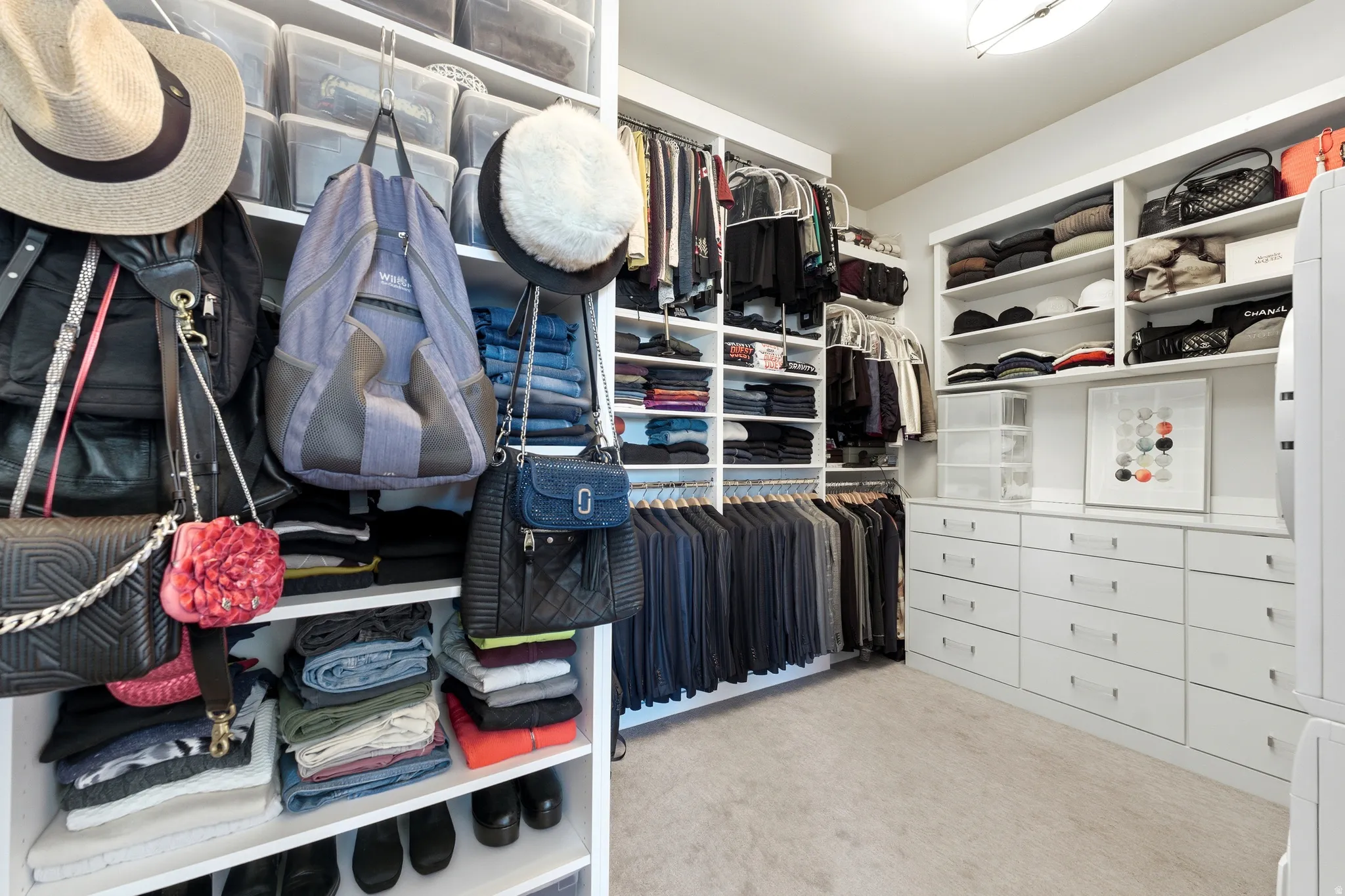 Custom closet system featuring extensive shelving, multiple hanging rods, built-in drawers, and overhead storage