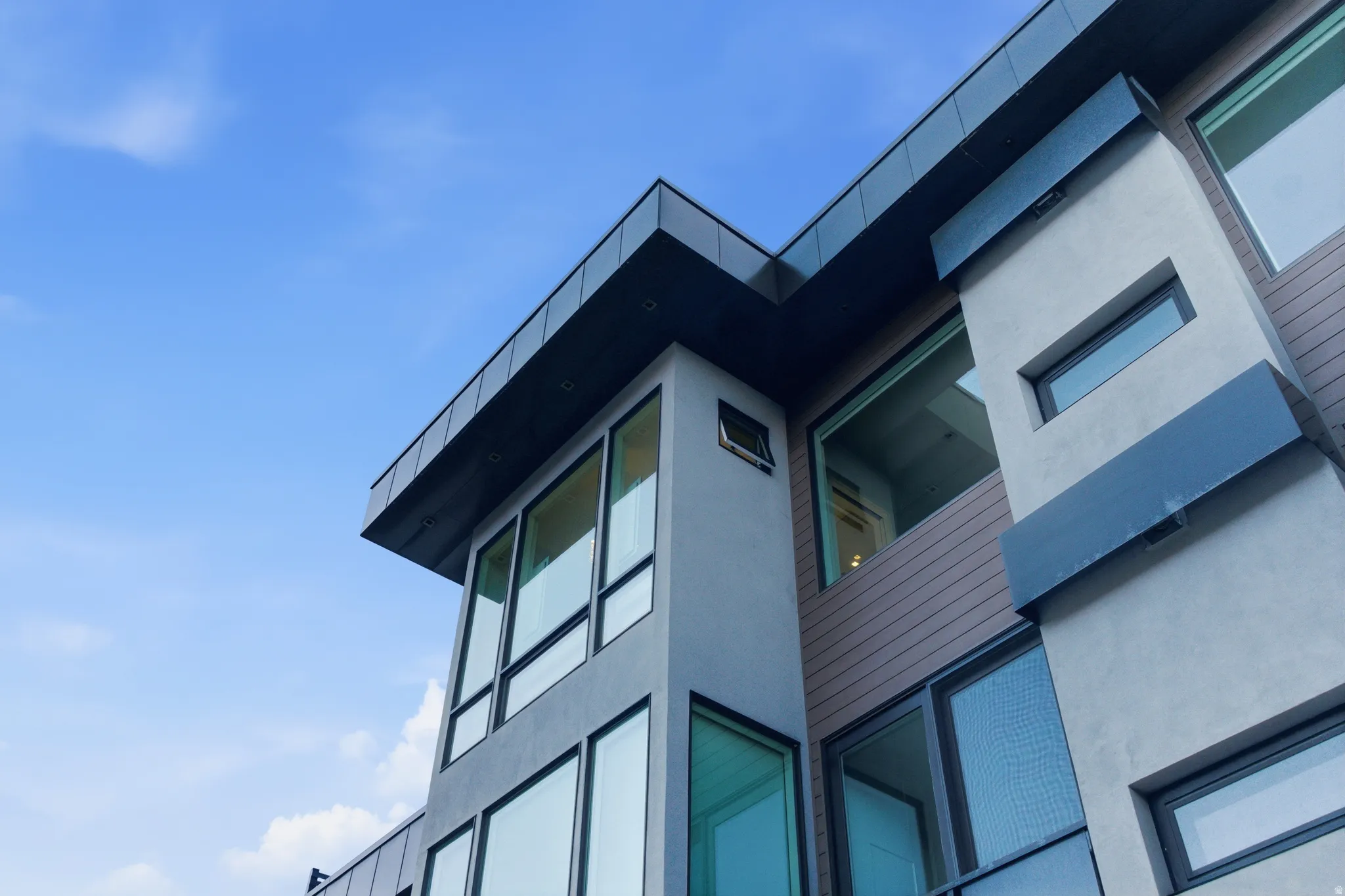 Contemporary exterior featuring multiple large-pane windows, a flat roofline, and varied facade materials including stucco and horizontal siding