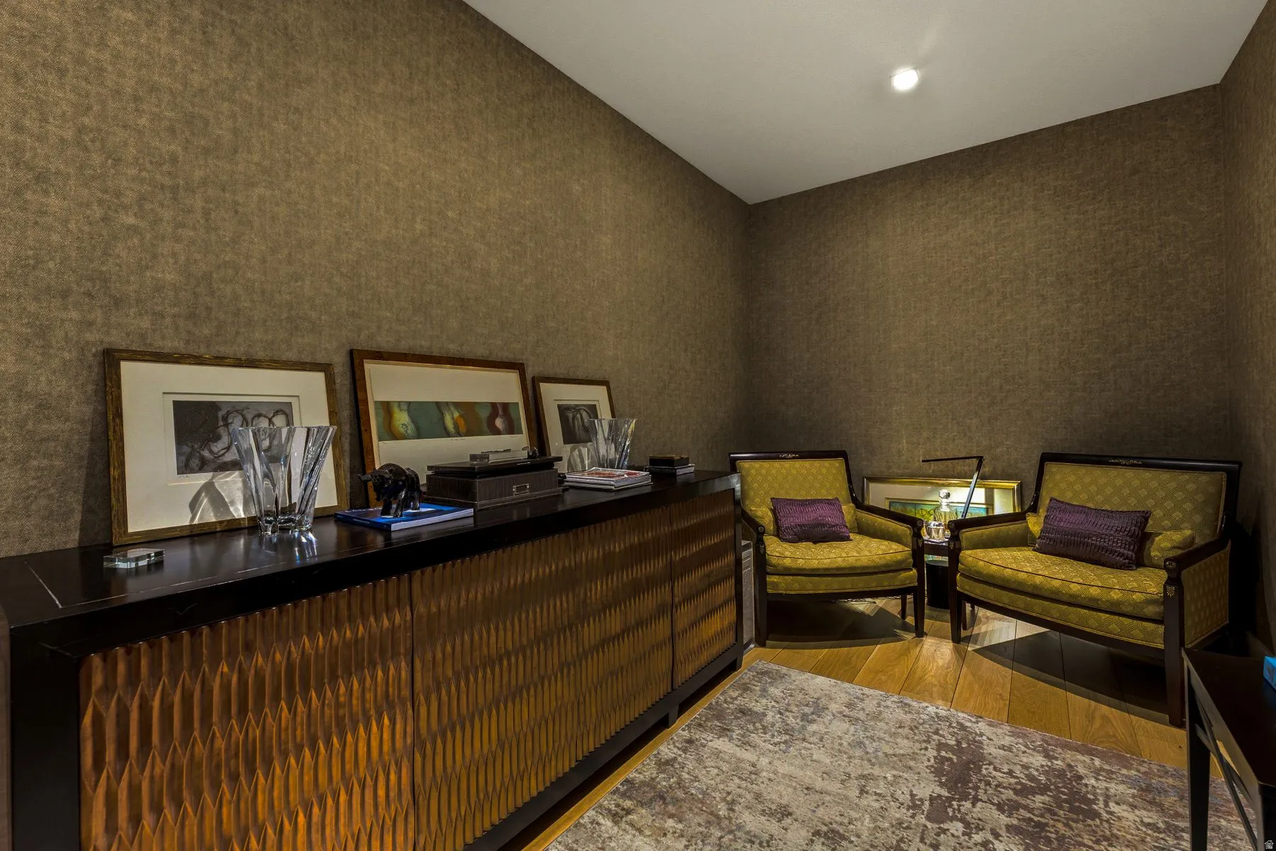 Textured wall covering in a warm tone, featuring a built-in credenza with a textured wood-finish facade and a dark countertop