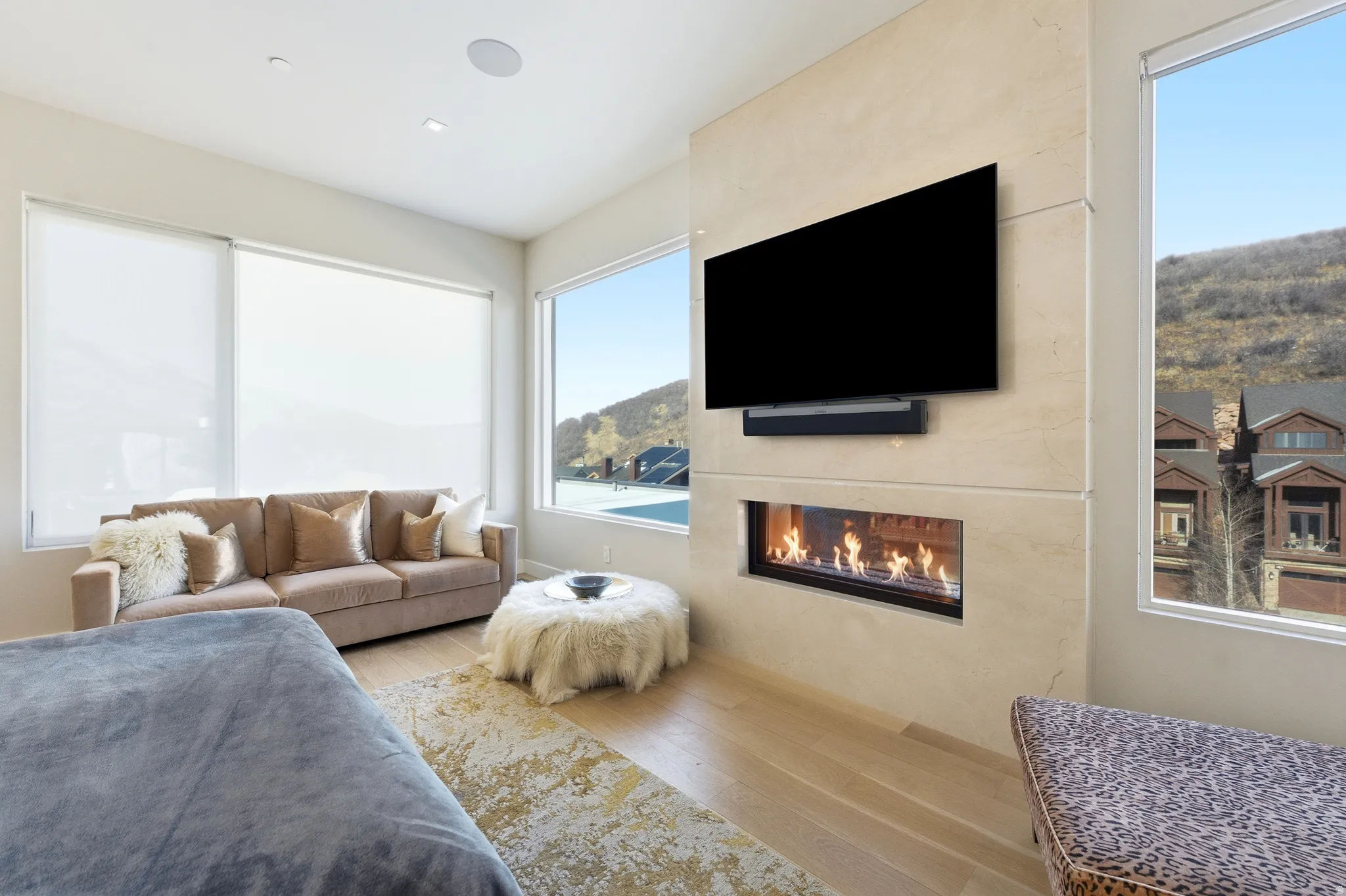 Integrated linear fireplace with a mounted television, set within a light-toned stone-finish wall