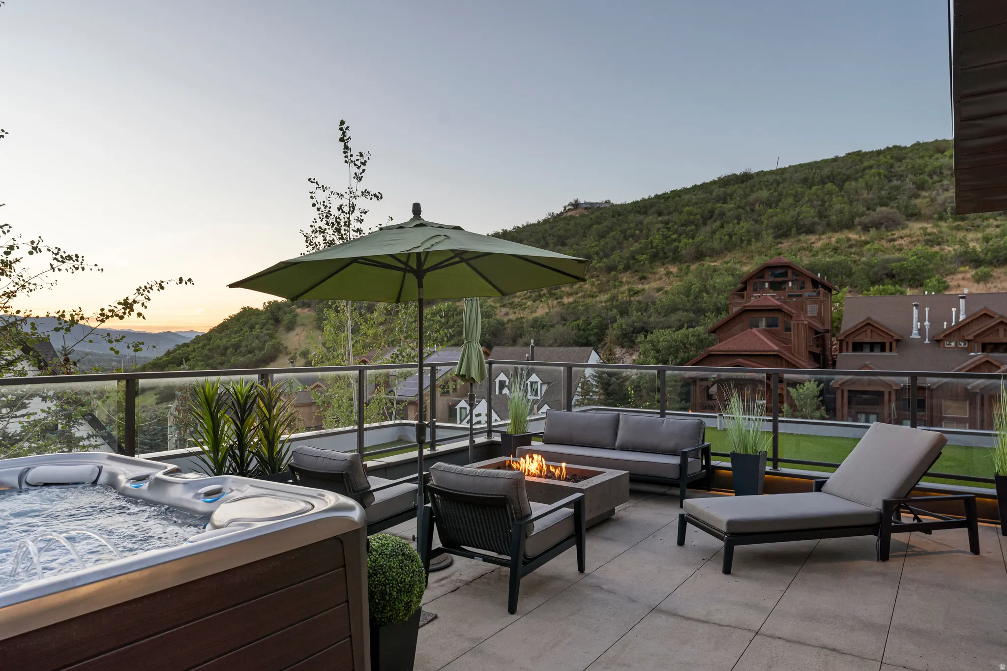 Expansive outdoor patio featuring a built-in hot tub, concrete tile flooring, and glass panel railings