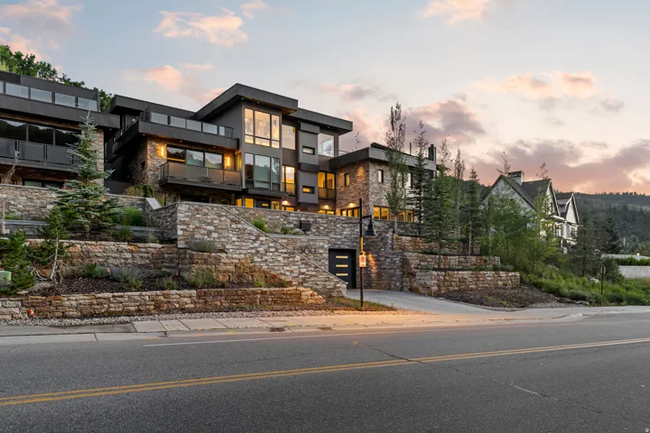 Contemporary multi-level residence featuring expansive windows, private balconies with glass railings, and a stone facade