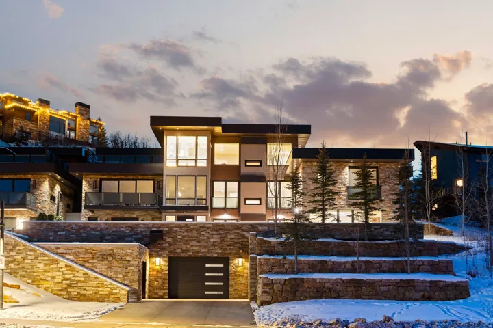 Contemporary architecture featuring extensive stone veneer siding and broad window expanses