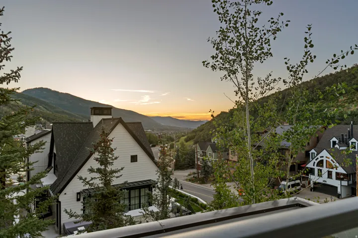 Modern mountain architecture with white siding and dark trim, featuring a prominent chimney structure and gabled roofline