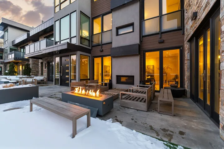 Modern outdoor patio featuring a linear gas fire pit, concrete pavers, and a stone accent wall