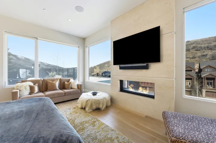 Integrated linear fireplace within a substantial stone-finish wall, featuring a mounted media screen