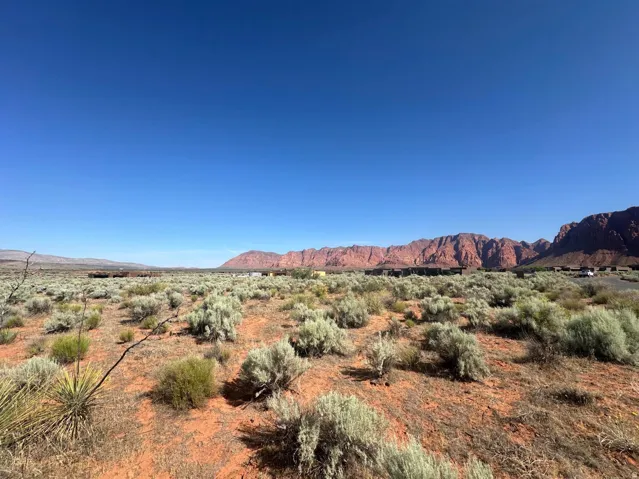 Expansive desert landscape featuring red rock formations and natural vegetation