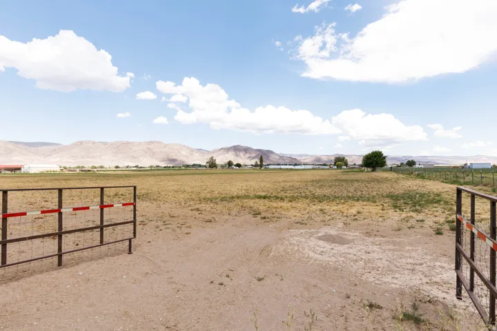 Expansive open land featuring metal gate entry and distant mountains