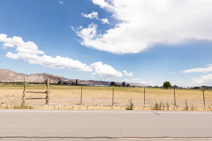 Expansive rural landscape featuring a paved road, a wooden fence, and open fields