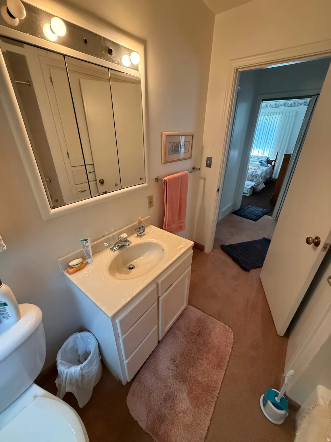 Bathroom with a single vanity featuring a built-in sink, base cabinetry, and a mirrored medicine cabinet with integrated lighting