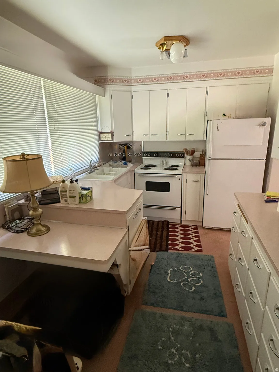 Kitchen featuring white upper and lower cabinetry, white appliances, and a built-in desk area