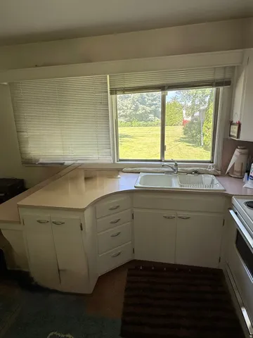 Kitchen featuring a double-basin sink, light-toned countertops, and extensive white cabinetry