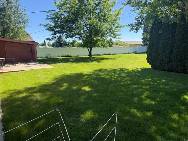Expansive backyard featuring a lush lawn, mature trees, and a full privacy fence