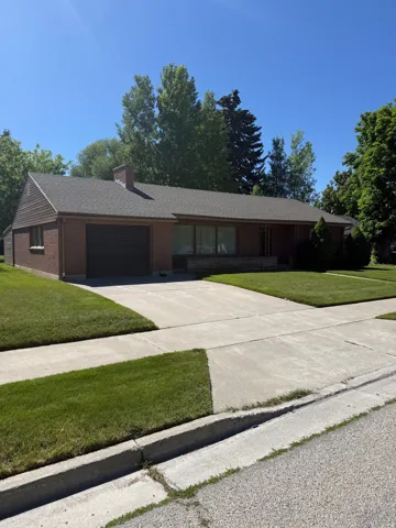 Brick exterior home featuring a dark shingle roof, integrated garage, and a concrete driveway