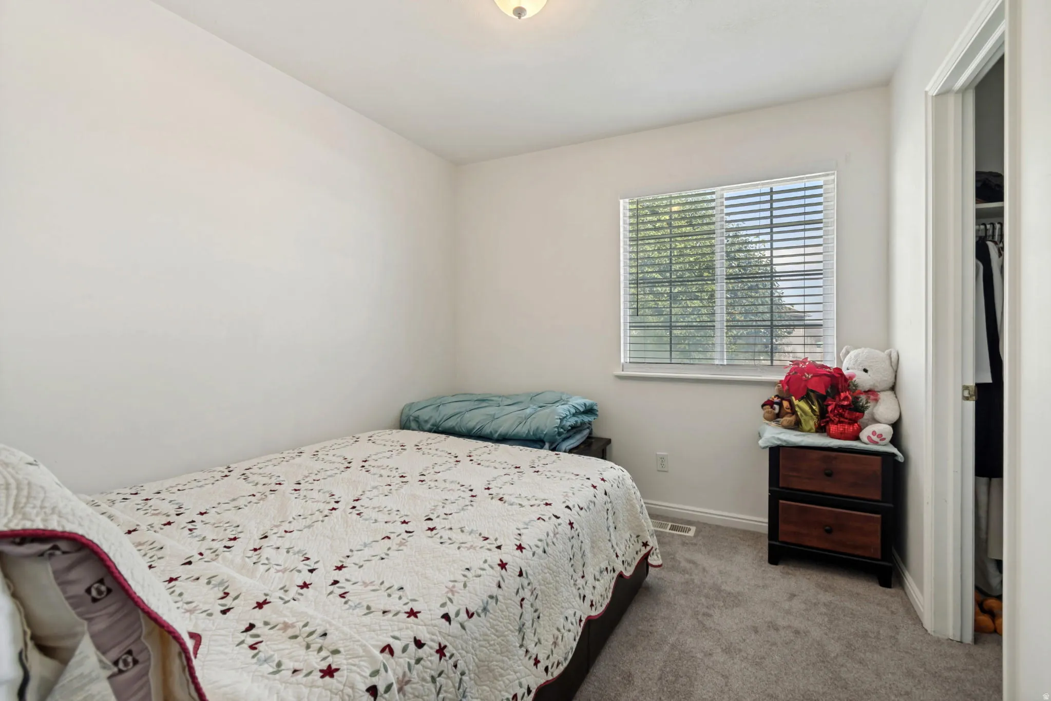 Carpeted room featuring a single window with blinds, white walls, and a ceiling-mounted light fixture