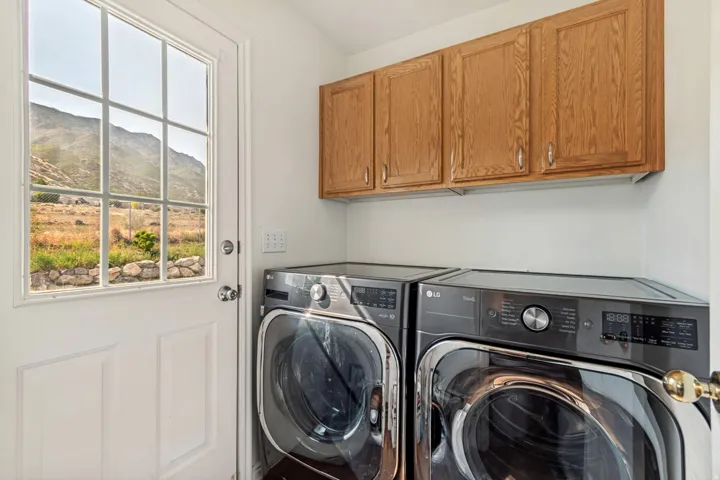 Laundry area with ample natural light, upper wood cabinetry, and a glass-paneled door