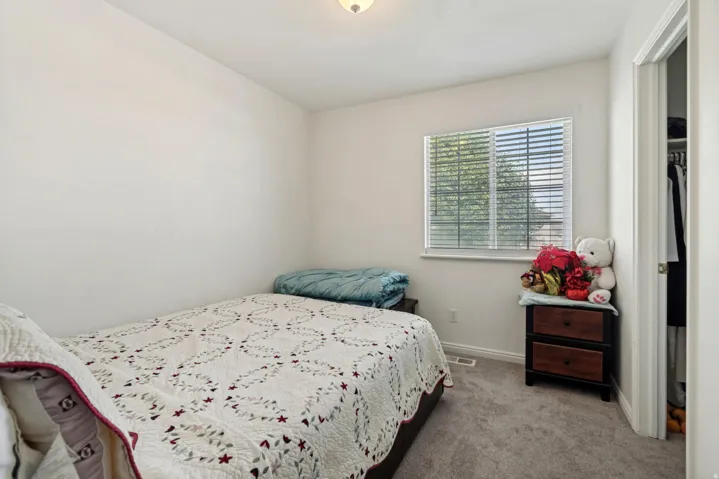 Carpeted room featuring a single window with blinds, white walls, and a ceiling-mounted light fixture