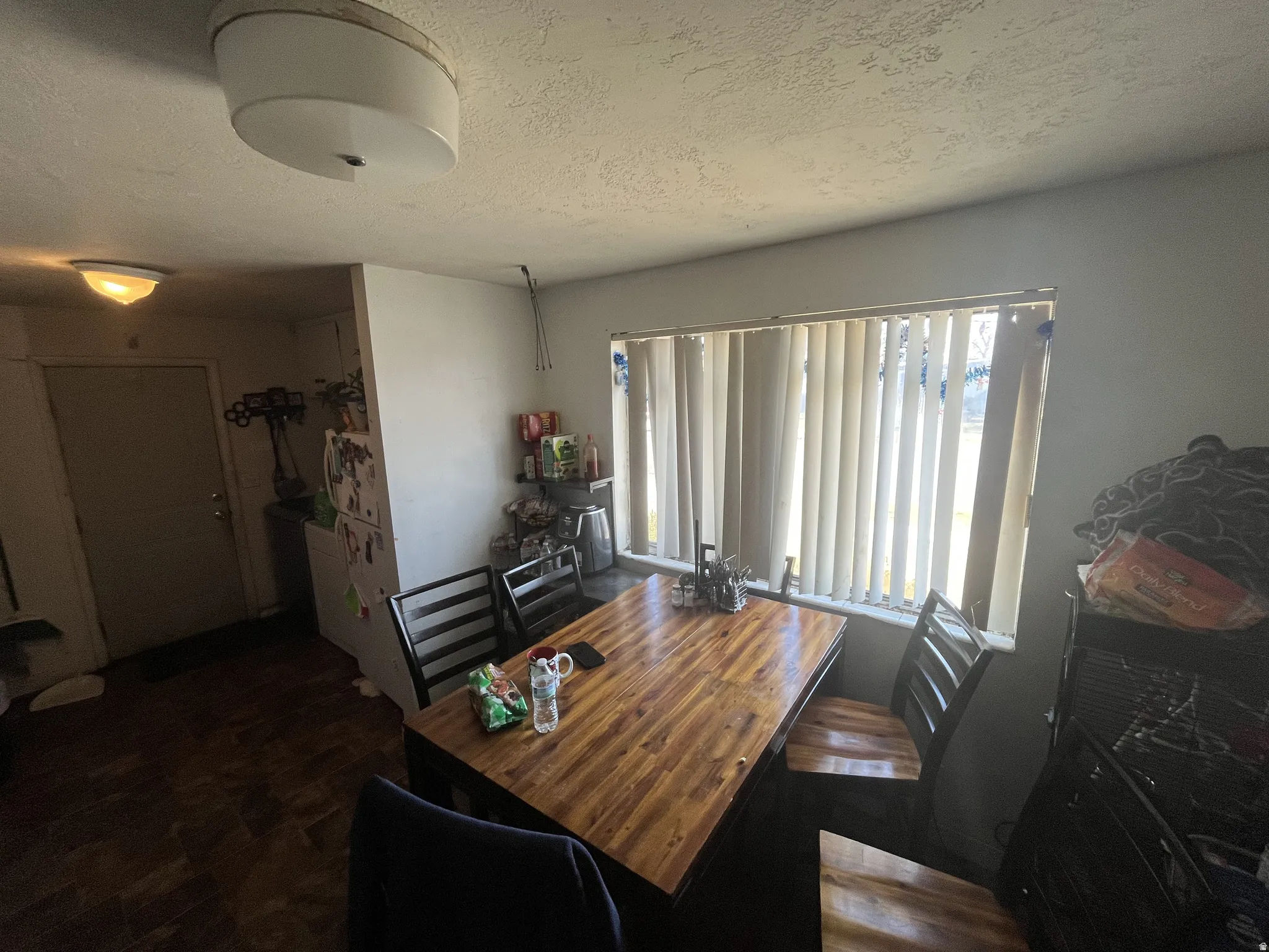 Dining area featuring a wood-finish table, a window with vertical blinds, and hard surface flooring