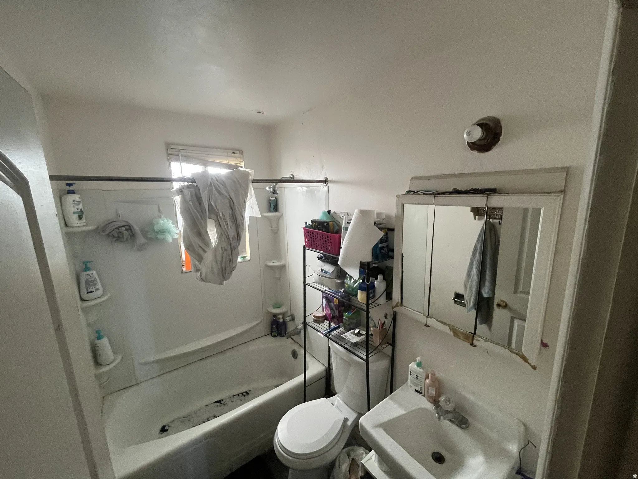 Bathroom featuring a white porcelain sink with a chrome faucet, a white medicine cabinet, and a white bathtub with a shower curtain rod