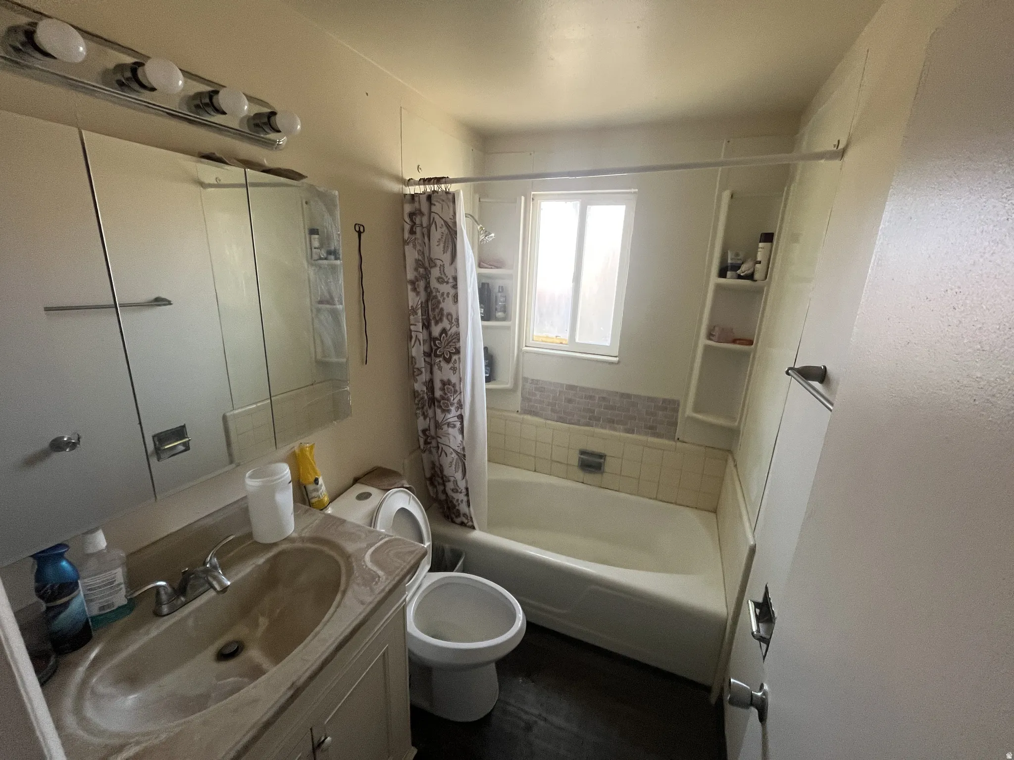 Bathroom featuring a built-in tub with tile surround, a single window, and shelving