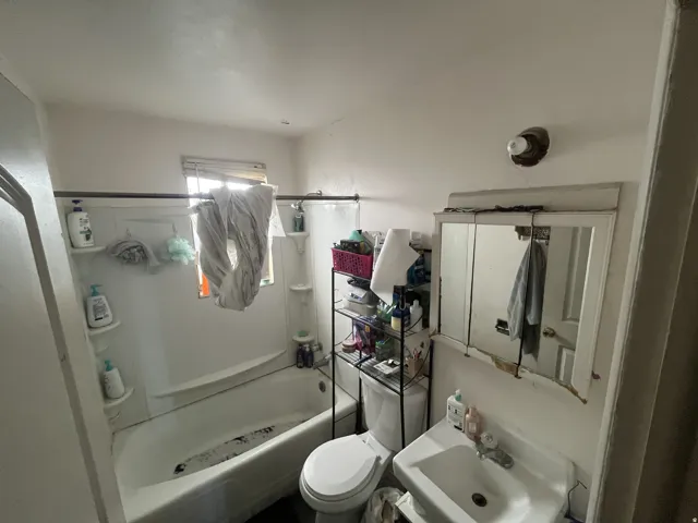 Bathroom featuring a white porcelain sink with a chrome faucet, a white medicine cabinet, and a white bathtub with a shower curtain rod