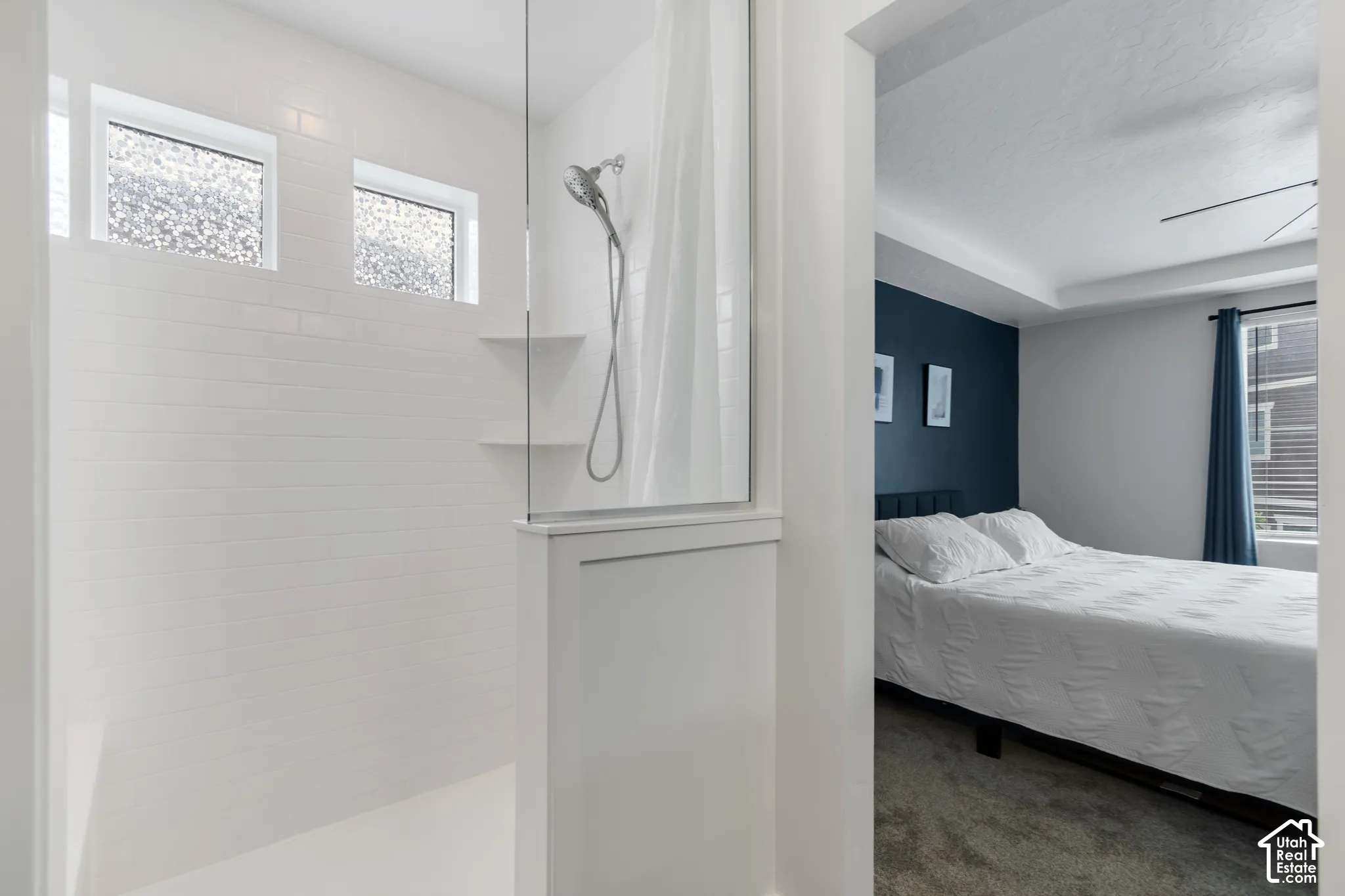 White subway tile shower surround with two upper transom windows and a glass enclosure