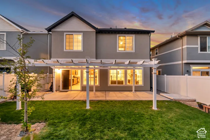Rear exterior with a concrete patio, a white pergola, and a private vinyl fence