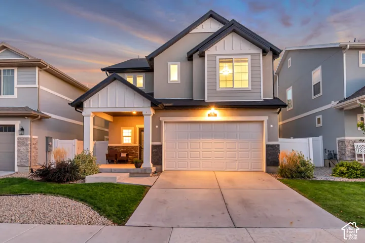 Contemporary exterior with a covered porch, stone accents, and a two-car garage
