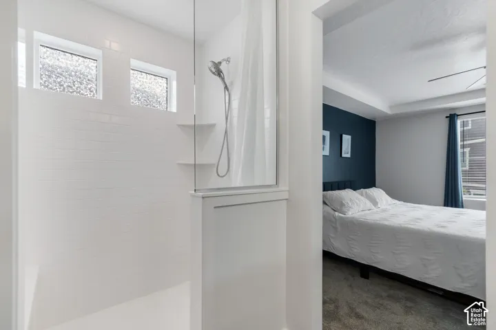 White subway tile shower surround with two upper transom windows and a glass enclosure