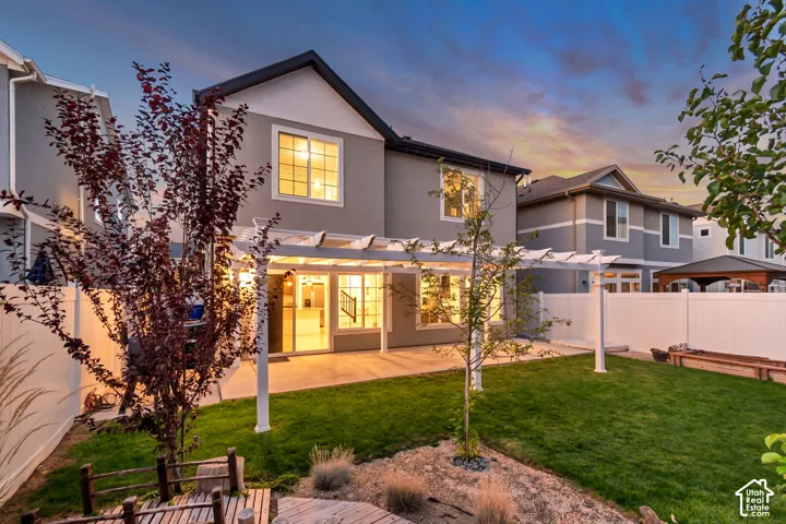 Expansive backyard featuring a manicured lawn, a white privacy fence, and a concrete patio with a pergola