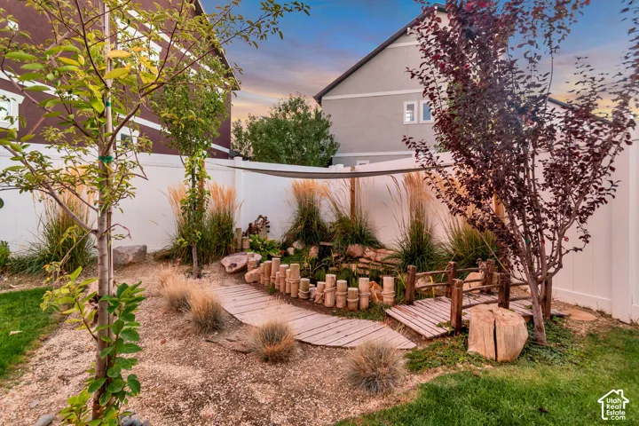 Landscaped yard featuring a wooden pathway, decorative bridge, and mature trees