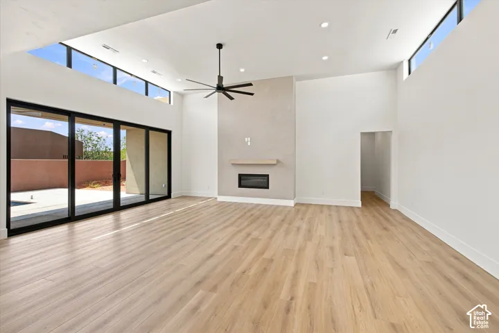 Vaulted ceilings with clerestory windows, wood-finish flooring, linear fireplace with mantel, and expansive sliding glass doors