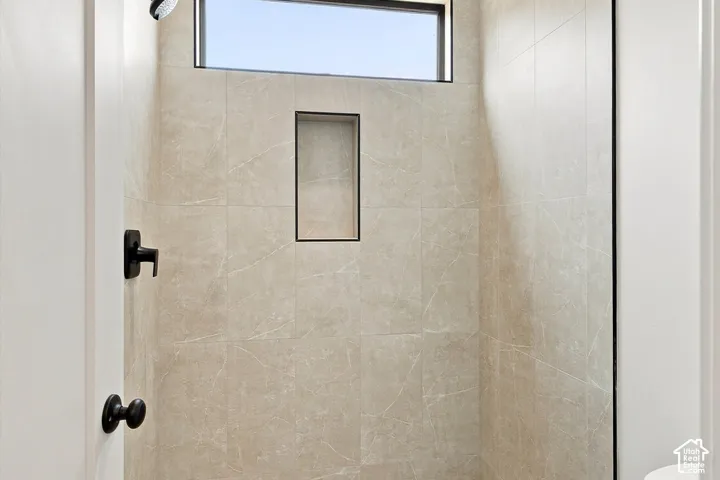 Tiled shower enclosure featuring a rectangular transom window, matte black framed shower niche, and matte black shower fixtures