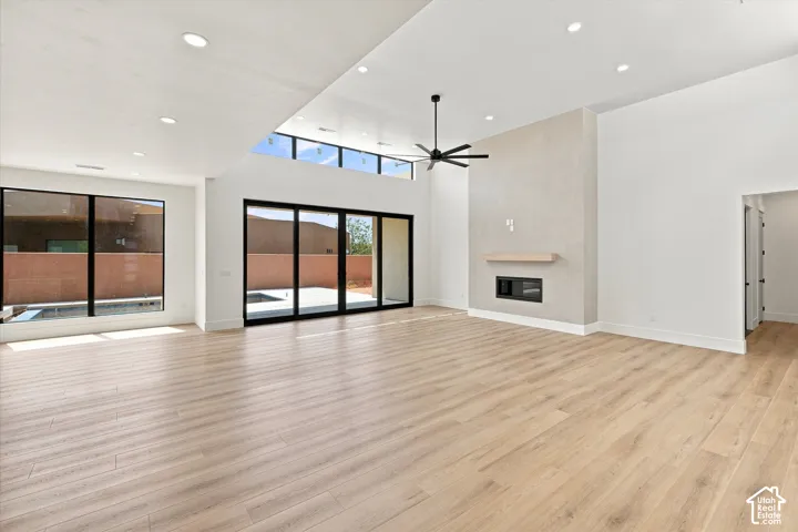 Expansive living space featuring wood-finish flooring, a contemporary fireplace, and a vaulted ceiling with clerestory windows