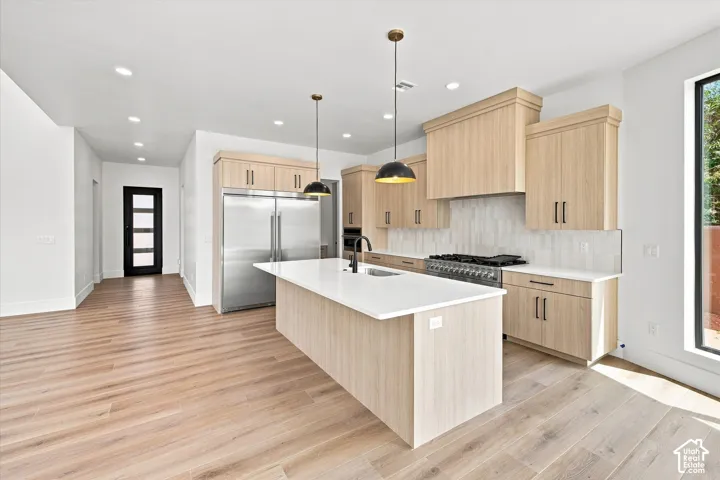 Spacious kitchen featuring wood-finish cabinetry, a large center island with a white countertop, stainless steel appliances, and wood-finish flooring