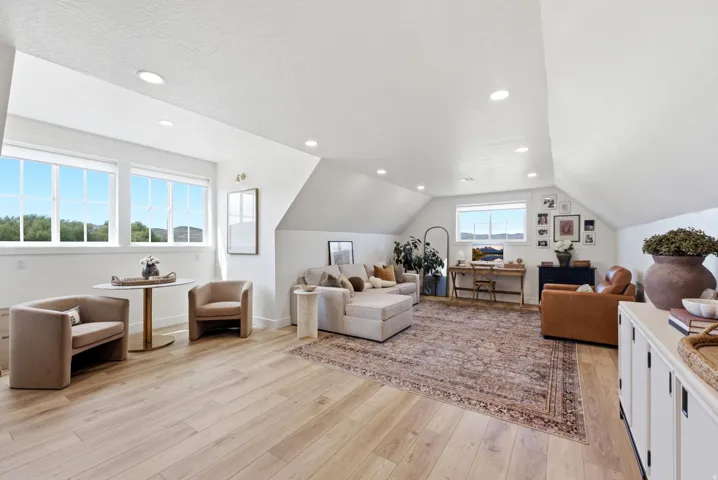 Spacious room featuring light wood-finish flooring, recessed lighting, and multiple windows
