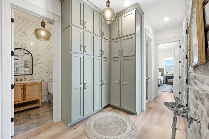 Built-in cabinetry with ample storage, light wood-finish flooring, stone accent wall, recessed lighting, and a prominent pendant light fixture