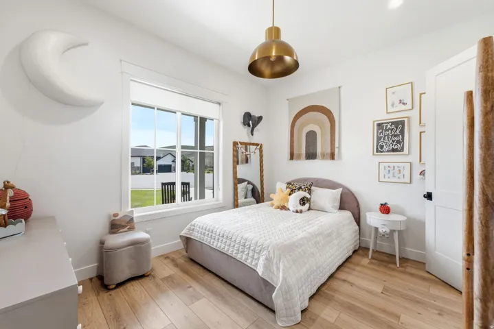 Bright bedroom featuring a large window, recessed lighting, and wood-finish flooring