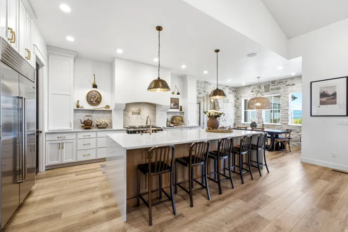 Gourmet kitchen featuring a large central island with seating, stainless steel appliances, and white cabinetry