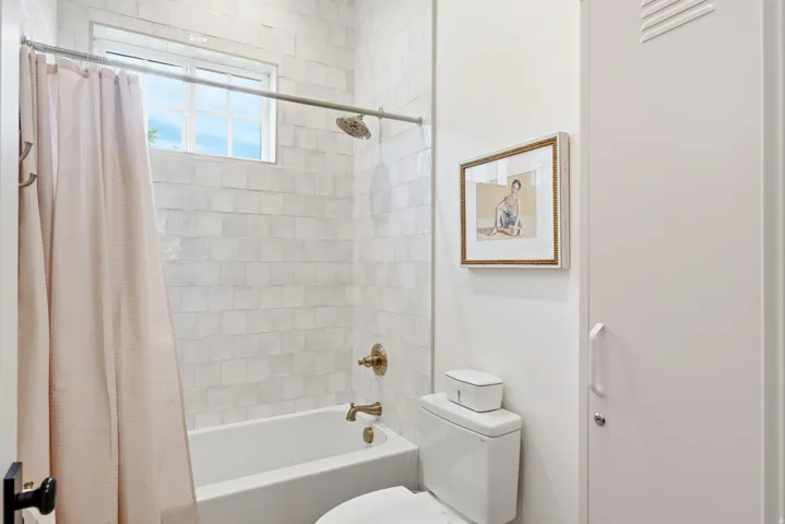 Bathroom featuring a white subway tile shower surround with a built-in tub, bronze fixtures, and an overhead window