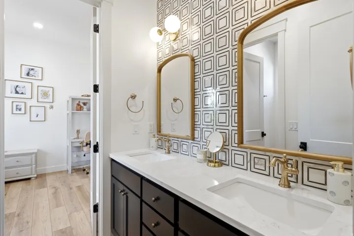 Bathroom vanity featuring dual under-mount sinks, a white countertop, and gold-finish fixtures