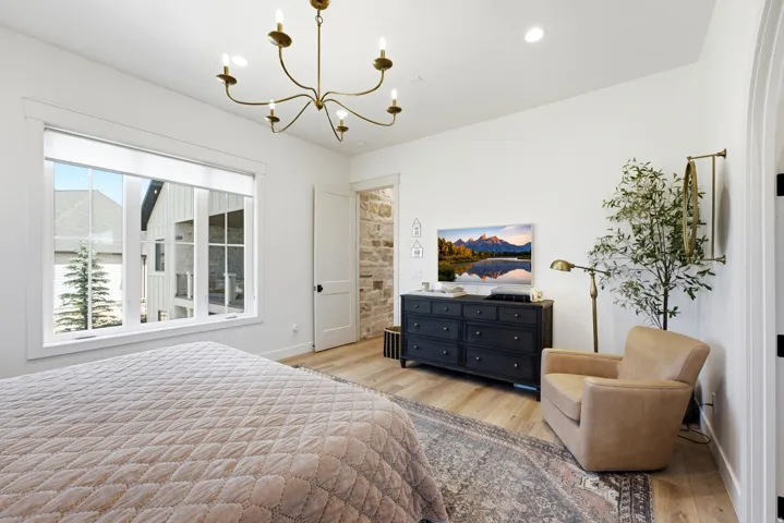 Bright room featuring a large window, light wood-finish flooring, a neutral wall color, and a multi-arm chandelier