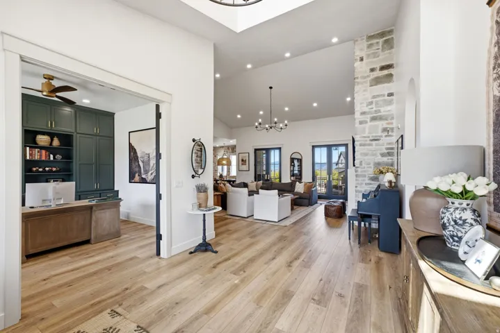 Spacious main hallway with wood-finish flooring, vaulted ceiling, and recessed lighting