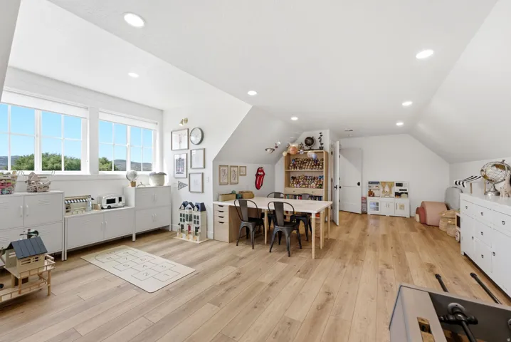 Spacious room featuring light wood-finish flooring, recessed lighting, and multiple windows