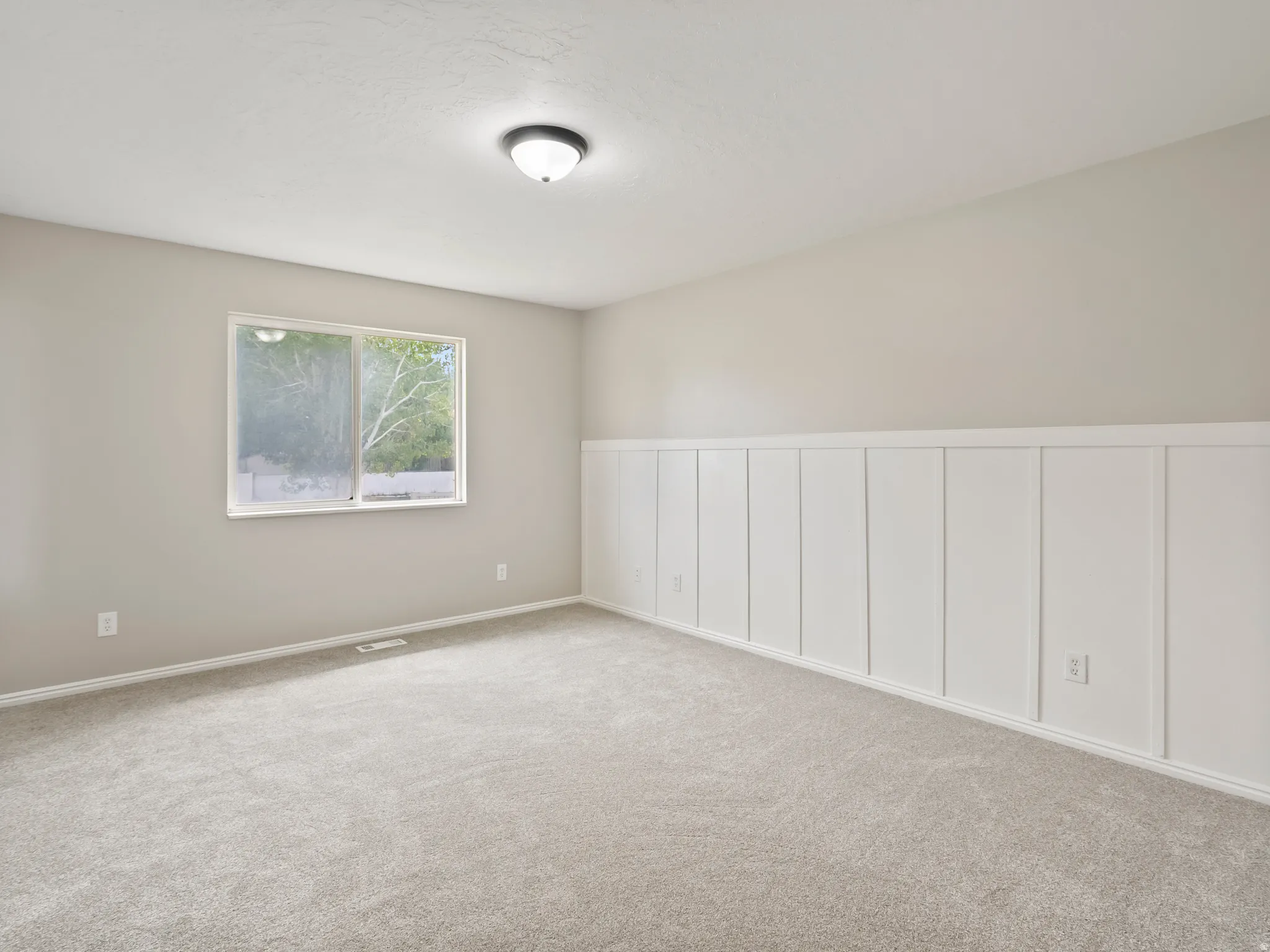 Carpeted room featuring a white board and batten accent wall, neutral wall paint, a double window, and a ceiling-mounted light fixture