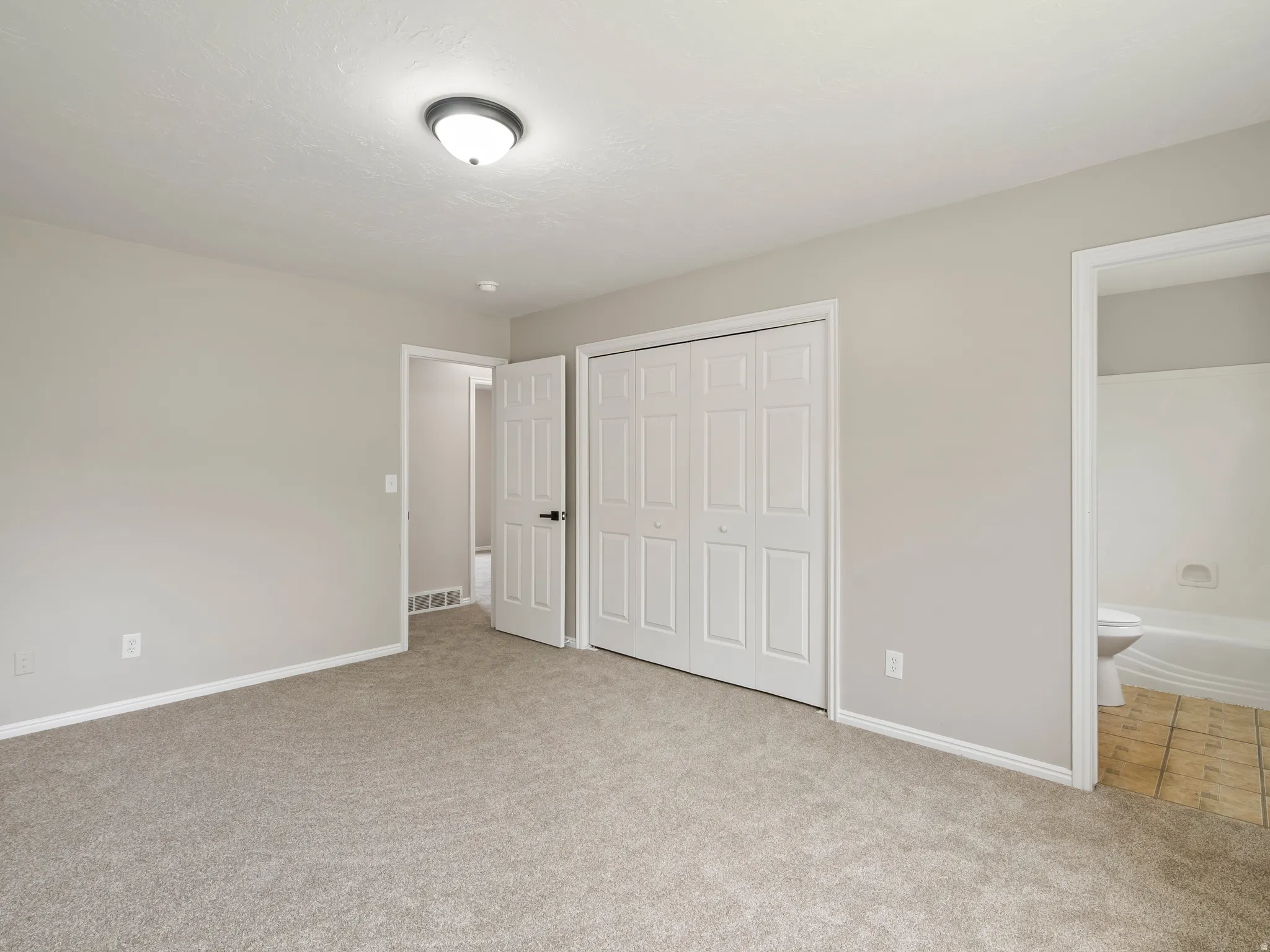 Spacious room featuring neutral carpeting, a flush mount ceiling light fixture, and light-toned walls