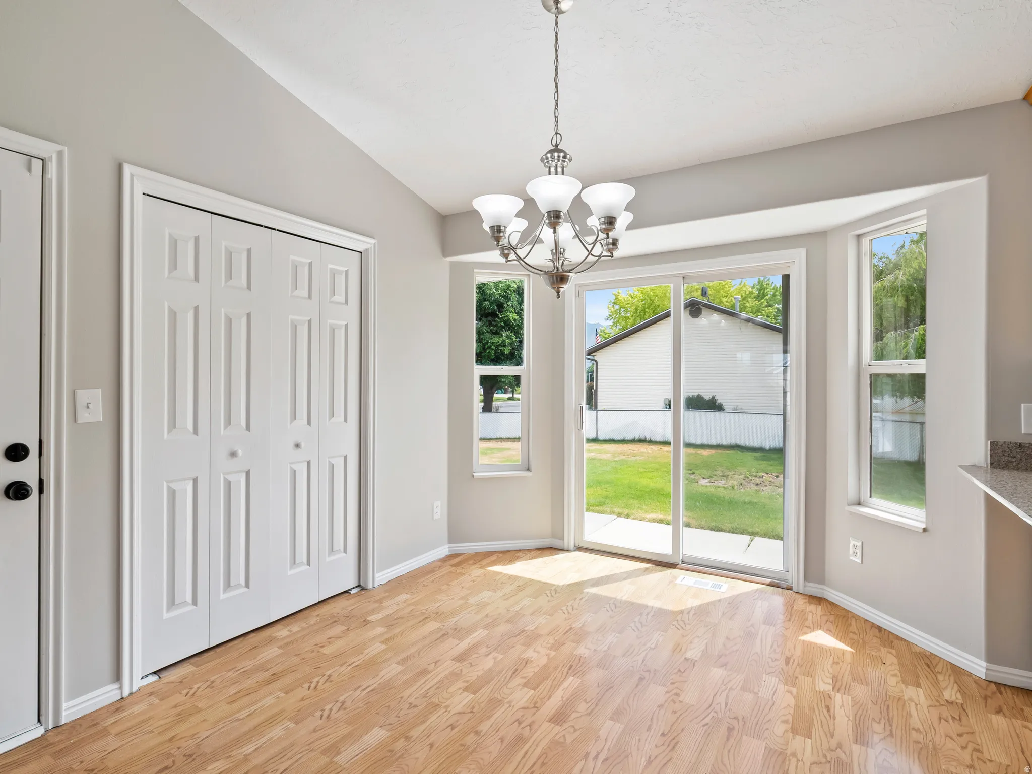 Dining area featuring wood-finish flooring, a contemporary chandelier, bright paint, white trim, and a sliding glass door to the backyard